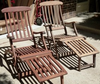 Pair of wooden slat lounge chairs with adjustable reclining backs and footrests outdoors