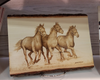 Woodburned artwork of three running horses on a natural-edge wood slab