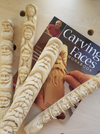 Woodcarving study sticks with carved faces displayed on a workbench alongside Harold Enlow's Carving Faces workbook.