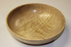 Smooth, shallow wooden bowl with visible grain patterns, turned on a lathe.