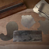 Various shaped card scrapers and a burnisher tool on a wooden workbench surface.