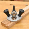 Router plane with black handles set on wood piece with routed groove on workbench