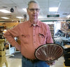 Older man in workshop holding segmented wood bowl with geometric pattern inside