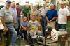 Group of woodworkers gathered around a lathe with a segmented bowl blank mounted for turning.