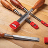 Set of five woodturning chisels with wooden handles and red protective blade covers on a wooden workbench