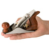 Hand holding a low-angle block plane with wooden handles and brass adjustment knob.