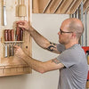 Woodworker organizing chisels and carving tools on a wall-mounted rack in workshop