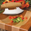 Curved ulu knife with wooden handle resting on segmented wooden cutting board with chopped vegetables