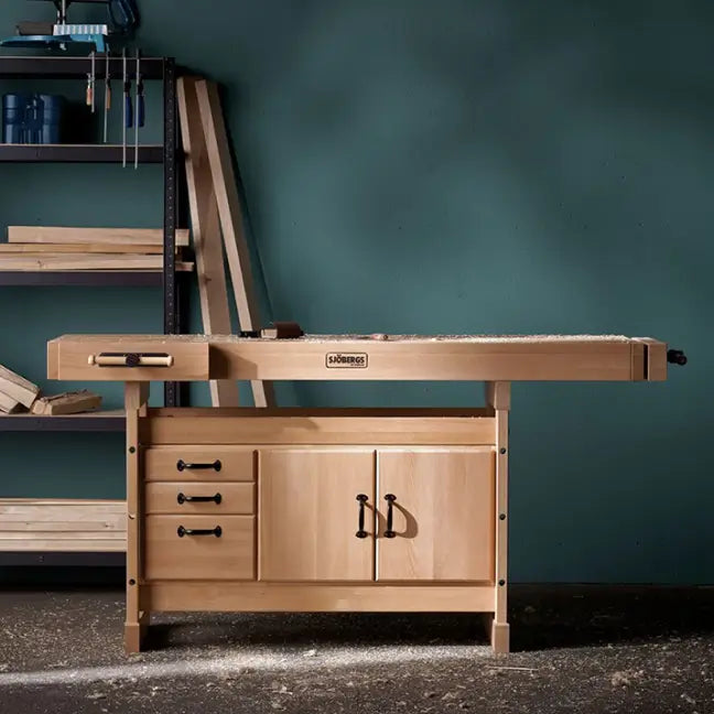 Wooden workbench with drawers and a cabinet in a workshop setting.